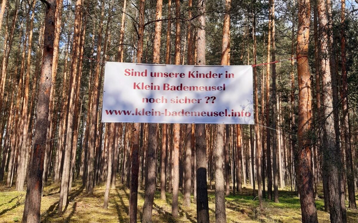 Großes Plakat im Wald, mit dem Text: "Sind unsere Kinder in Klein Bademeusel noch sicher? www.klein-bademeusel.info"